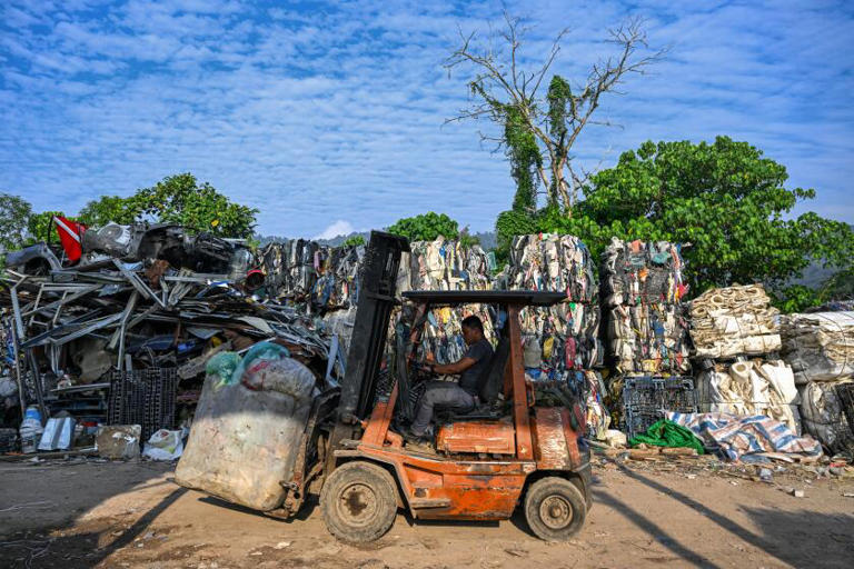 A worker transports plastic waste slated for a compressor in Bentong, Malaysia, in June 2024 before the waste is recycled and sold. ((Mohd Rasfan / AFP/Getty Images))