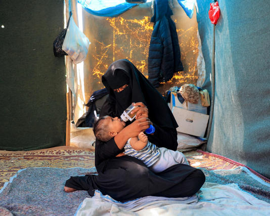 A woman feeds her child a formula of anise, due to lack of baby formula, in a tent at a camp in Khan Yunis. Photograph: Eyad Baba/AFP/Getty Images