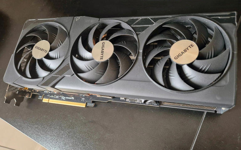 A Gigabyte RTX 4080 Super GPU sits on a black desk.