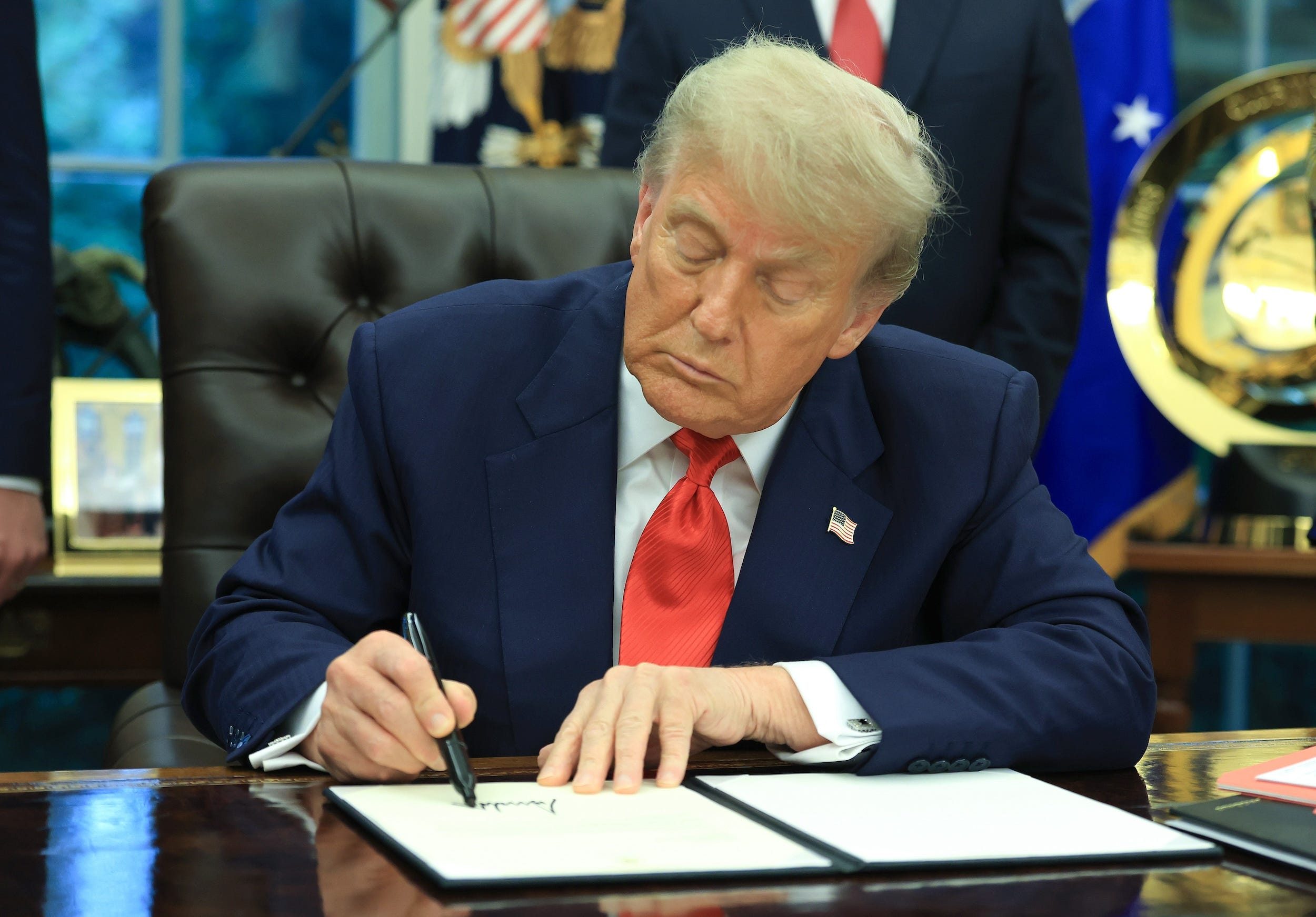 Donald Trump signs a formal letter in the Oval Office