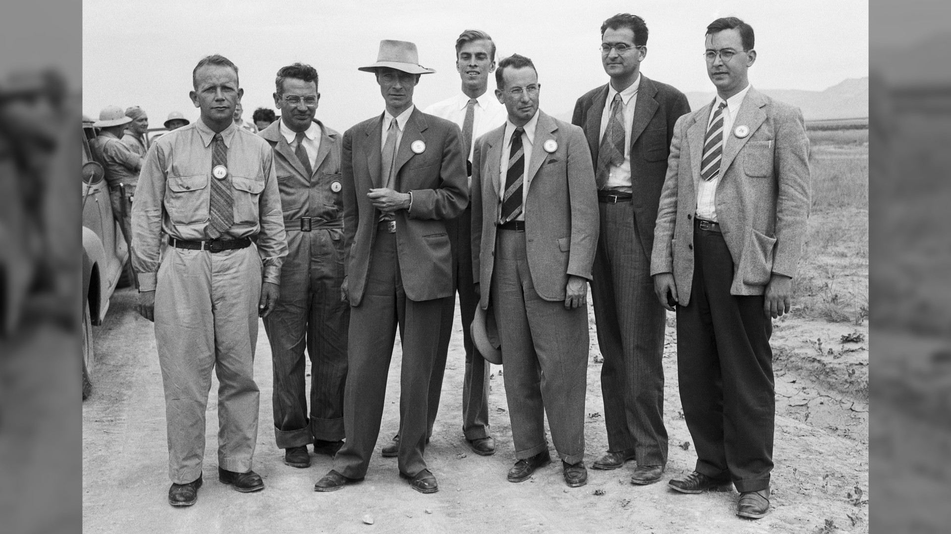 We see a black-and-white photo of famous scientists in suits at the bombing site.