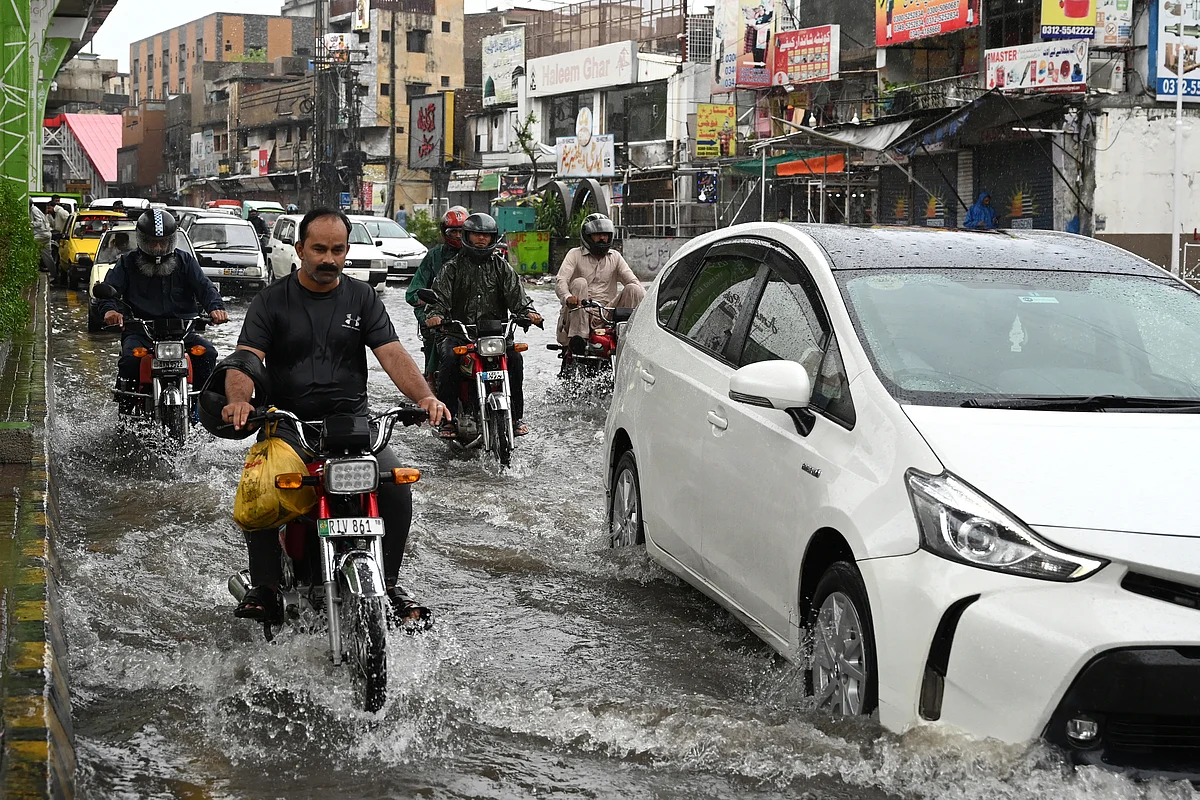 Commuters make their way through a flooded street during heavy monsoon rains in Rawalpindi on July 17, 2025.