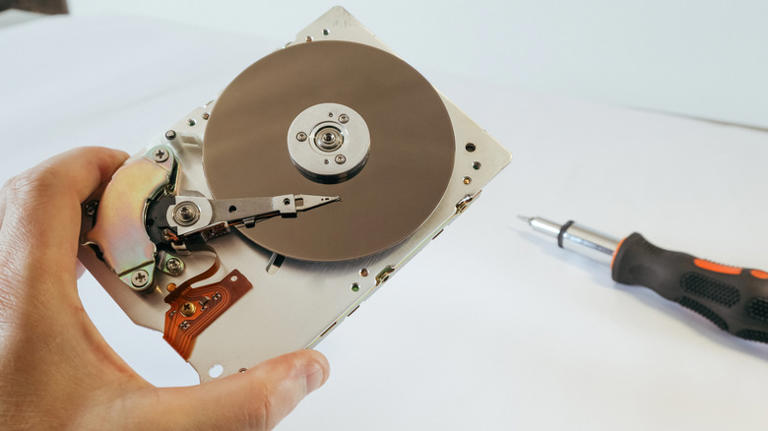 A open hard drive with a screwdriver near it