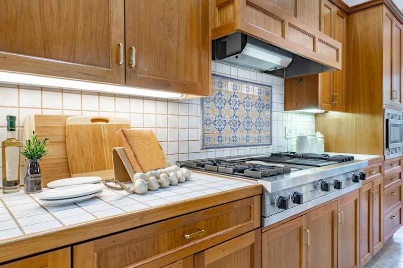 spacious mid century craftsman home kitchen with tiled countertops white appliances dining areas bar stools in white pine coloured cabinets mosaic backsplash