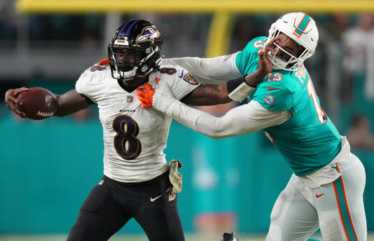 Madden 21 cover athlete Lamar Jackson stiff arms Miami Dolphins outside linebacker Jaelan Phillips during the second half at Hard Rock Stadium in Miami on Nov. 11, 2021.