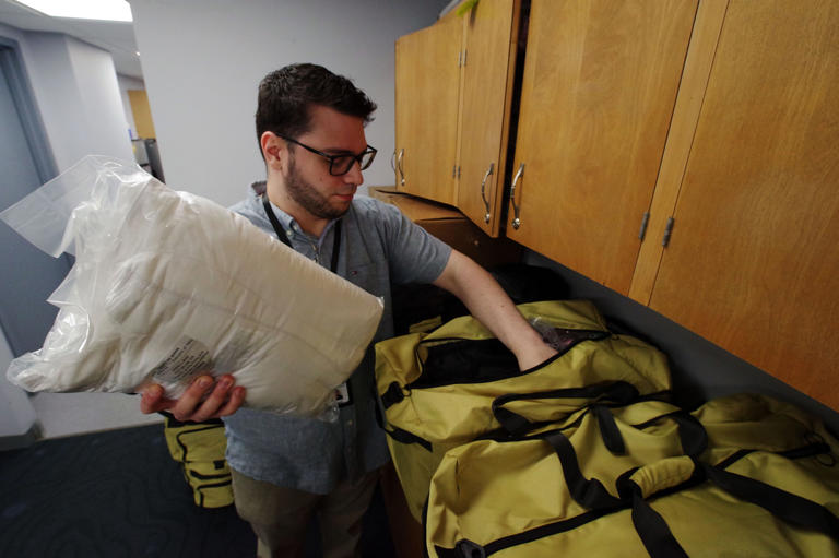 Yavier Castro-Soto, the parent advocate at the Brockton Public Schools Multilingual Family Communications Center, places a pillow into a duffel bag for homeless students in Plymouth County, Massachusetts, on Friday, July 11, 2025.