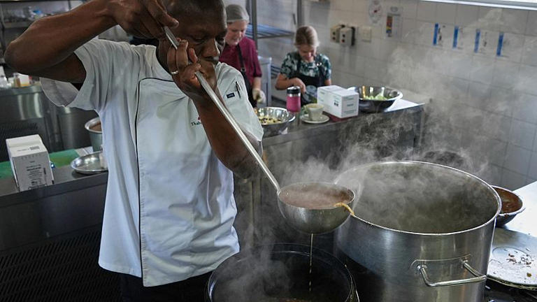 Le chef Thabo Letsholo utilise une louche pour remplir le seau de soupe à Johannesburg, en Afrique du Sud, le vendredi 18 juillet 2025.