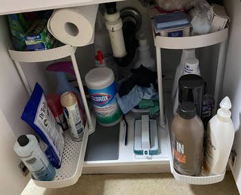 Organized under-sink storage with cleaning supplies, toiletries, and paper towels