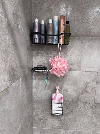 Shower corner with products like shampoo, body wash, a pink loofa on sleek wall racks