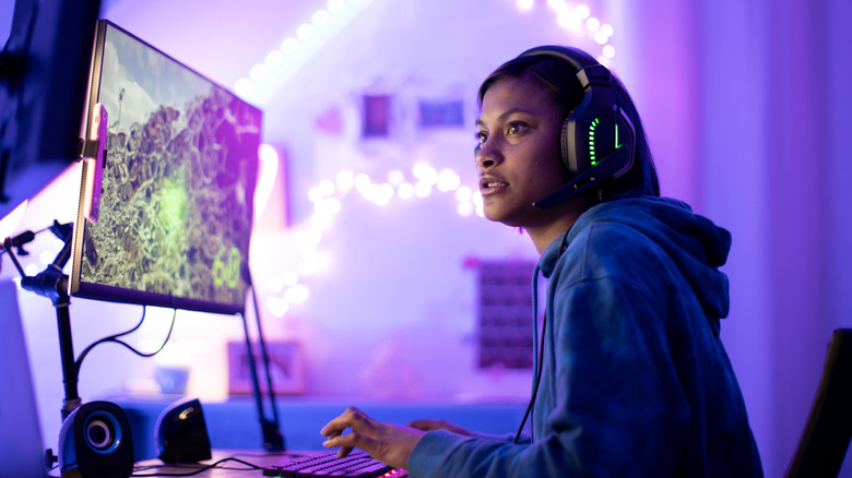 A person gaming on PC in pink room
