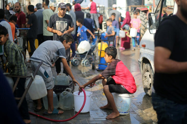 Palestinos enchem recipientes com água em um ponto de distribuição do campo de refugiados de Nuseirat, no centro da Faixa de Gaza, em 10 de julho de 2025