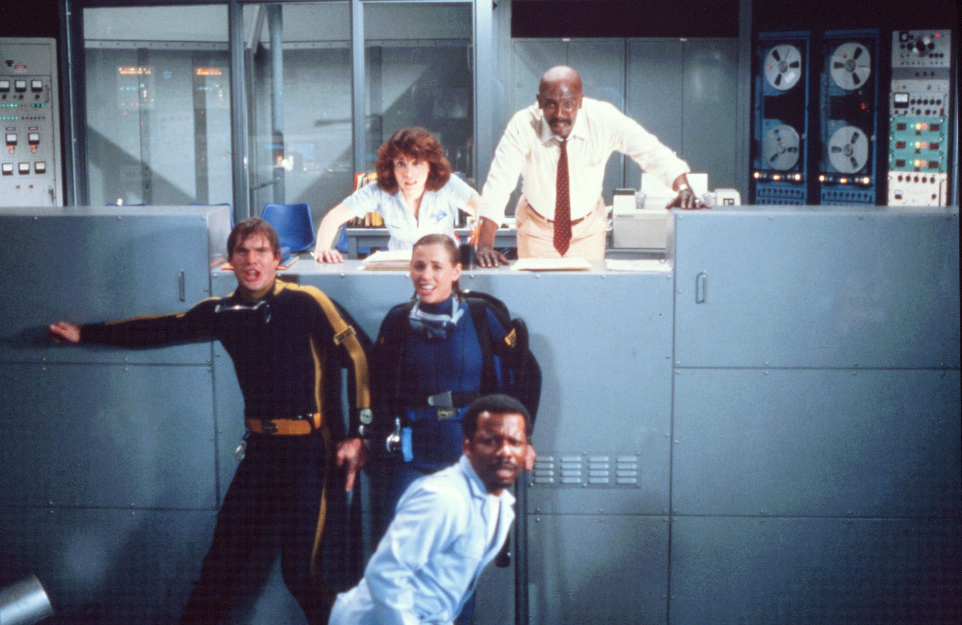 Dennis Quaid, Bess Armstrong, and Louis Gossett Jr appearing shocked in a control room in a scene from Jaws 3-D