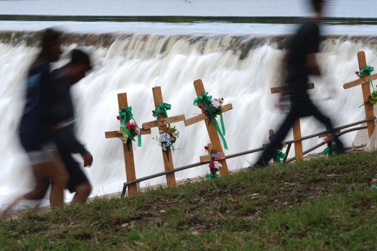 Eric Gay/AP - PHOTO: Visitors walk past crosses at a make-shift memorial honoring flood victims, Sunday, July 13, 2025, in Kerrville, Texas.