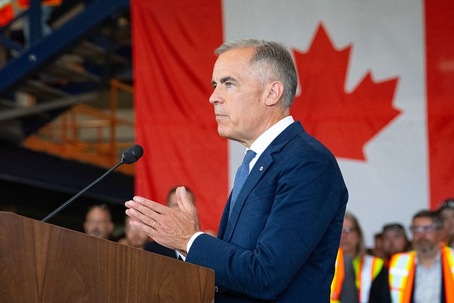 Mark Carney standing in front of a Canadian flag