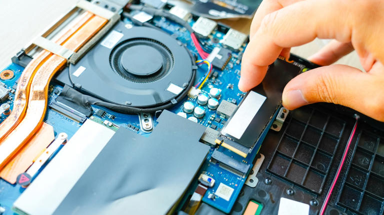 Repair engineer installs an M.2 NVMe SSD in a laptop
