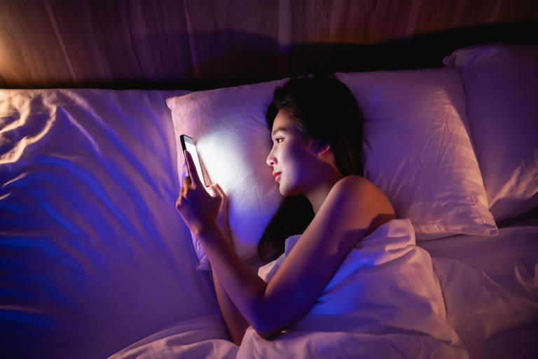 Hidden Health Tip - Person scrolling phone in bed, blue light glowing