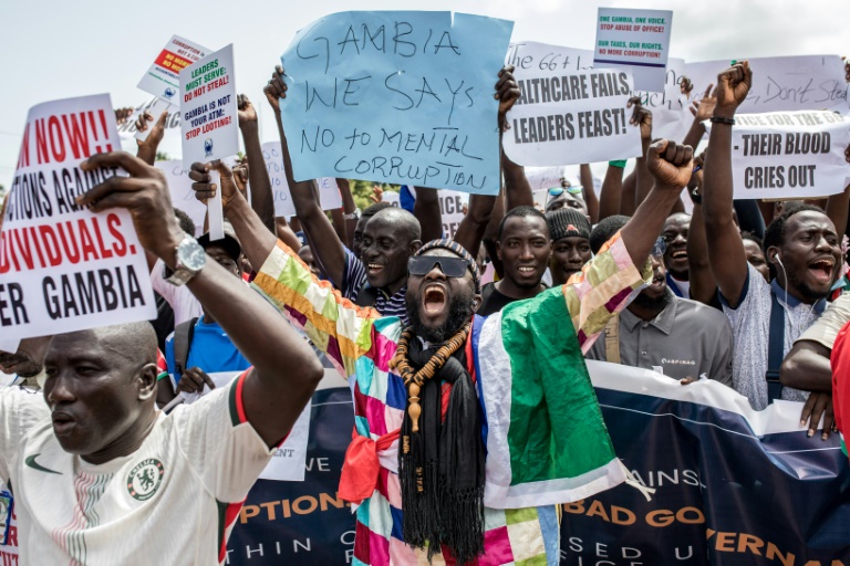 Des manifestants brandissent des pancartes à Banjul, capitale de la Gambie, le 23 juillet 2025. Des milliers de personnes ont manifesté le 23 juillet pour dénoncer, selon elles, la corruption et la mauvaise gouvernance dans le pays depuis l'arrivée au pouvoir en 2017 du président gambien Adama Barrow