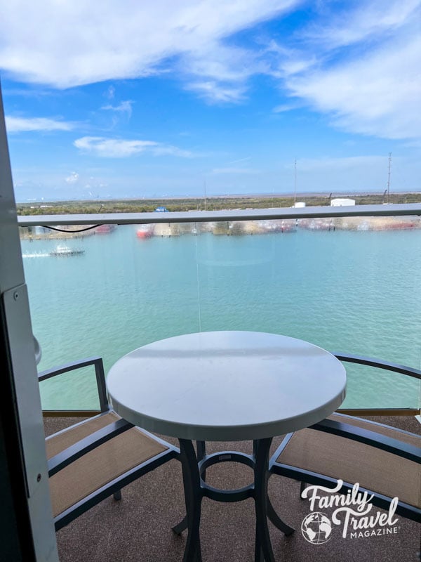 Stateroom balcony with table and two chairs with turquoise waters
