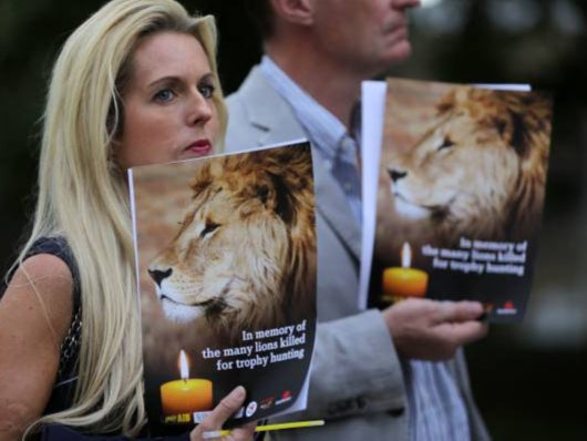 People hold candles and pamphlets shows an image of Cecil the lion at a vigil in central London on July 30, 2016 (AFP via Getty Images)