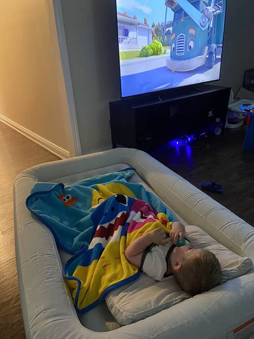 Reviewer's child sleeping on the gray mattress and watching tv