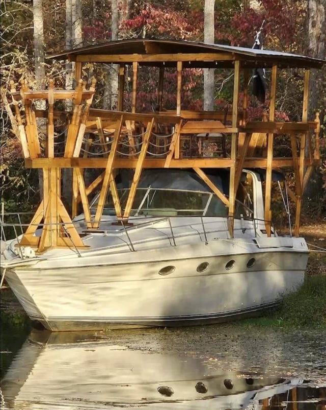 Boat with a wooden deck structure built on top, floating in a calm, wooded area
