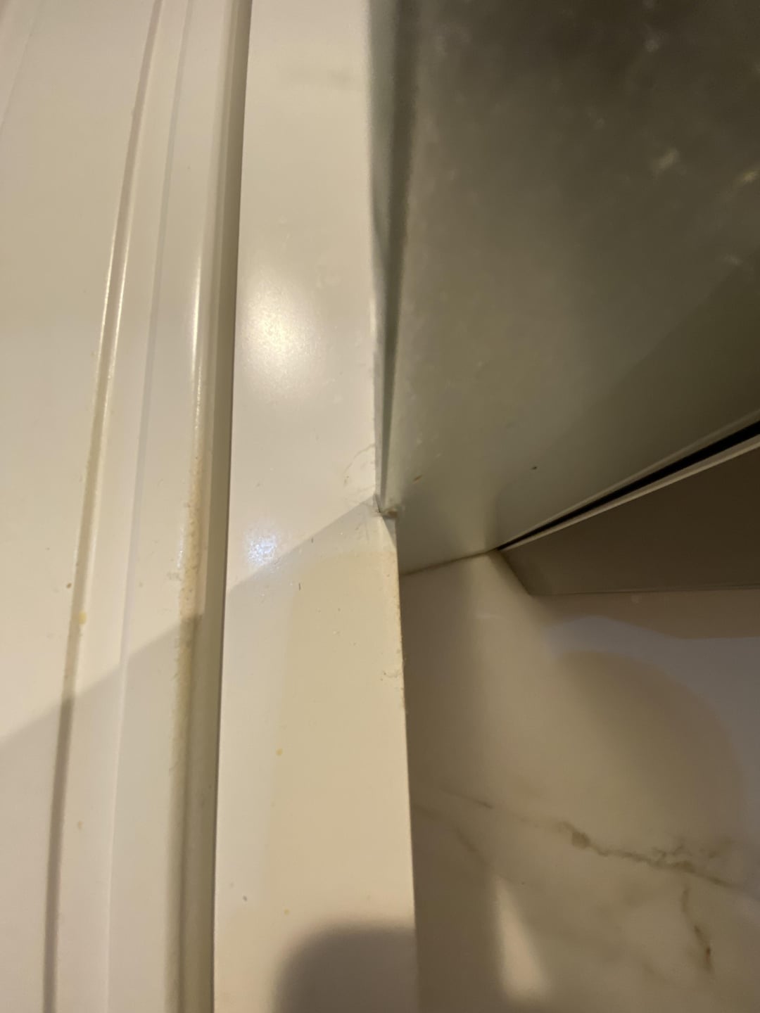 Close-up of a shower or bathtub corner showing a crack or gap between two sections