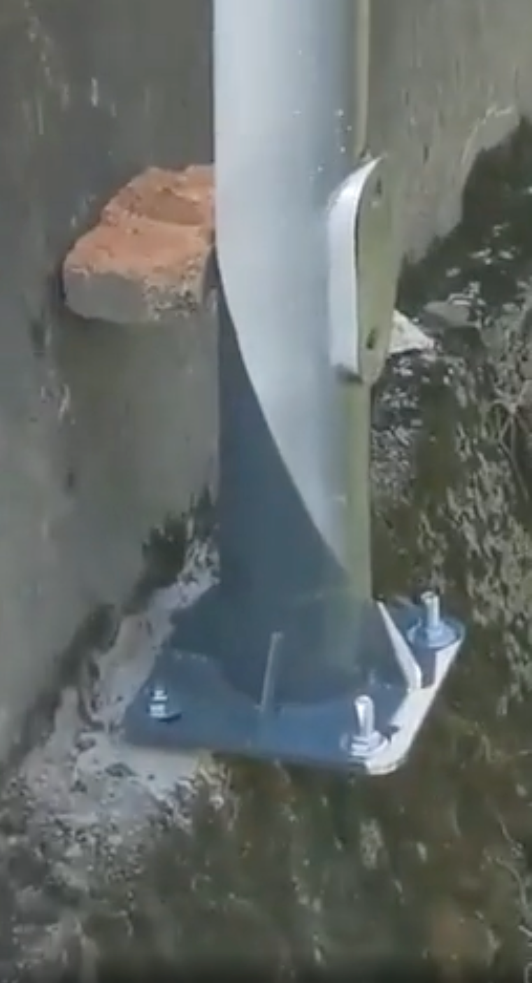 Support beam awkwardly attached to a wall with an unsecured brick, highlighting unusual construction methods