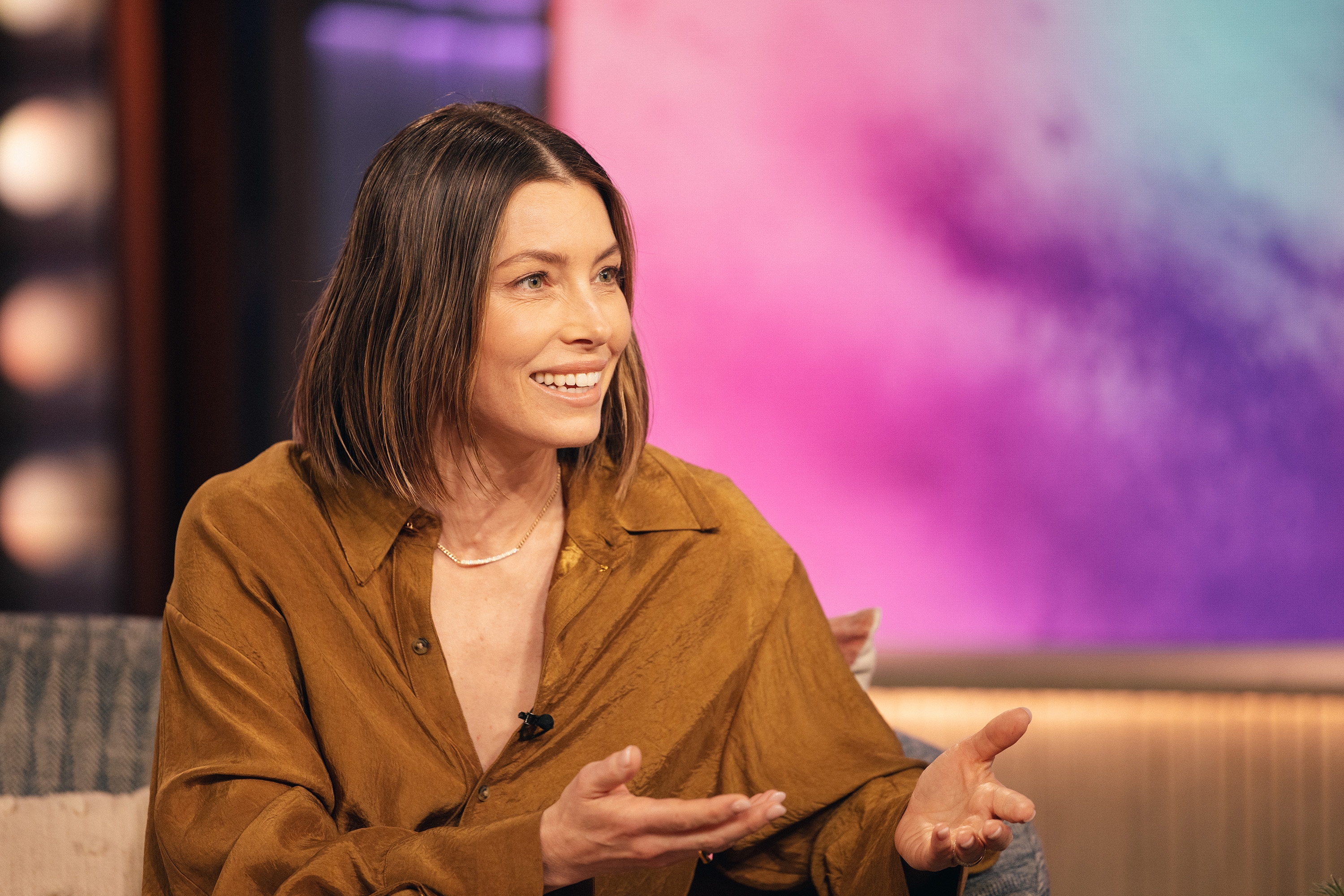 Jessica Biel in an interview setting, wearing a casual shirt, gesturing while speaking