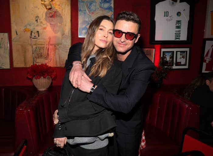 Justin Timberlake embraces Jessica Biel in a cozy room lined with art, wearing stylish casual outfits