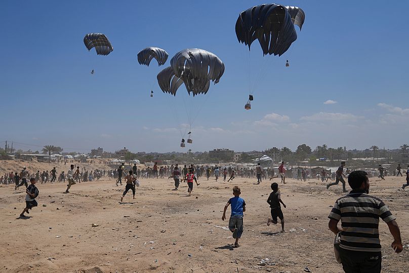 Palestinians rush to collect humanitarian aid airdropped by parachutes into Zawaida in the central Gaza Strip, 4 August, 2025