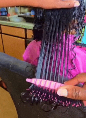 Stylist combs through wet curly hair in a salon to detangle it using a comb