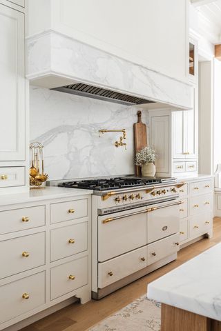 Elegant white kitchen with gold cabinet knobs.