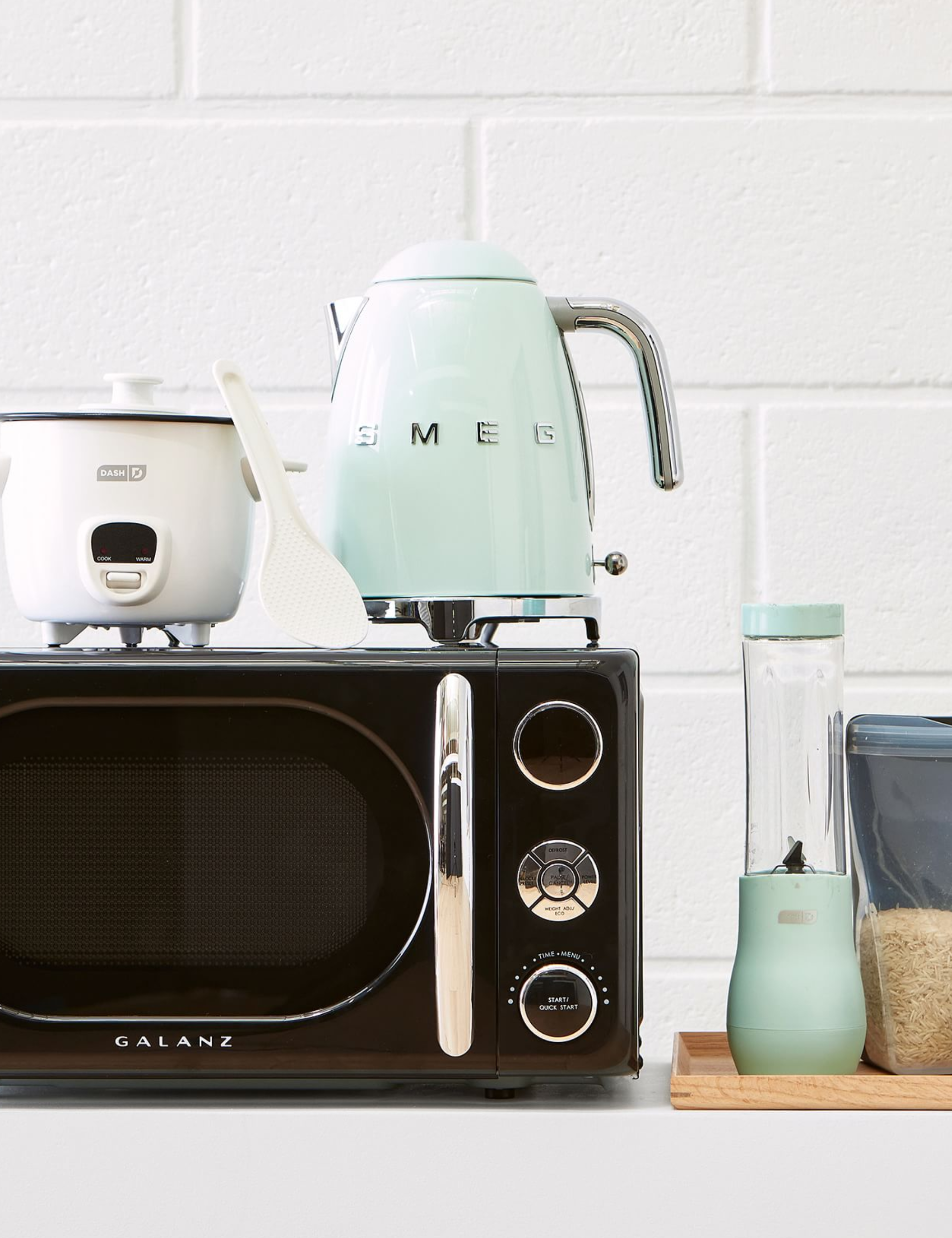 Dorm room kitchen appliances, inlcuding a microwave, mini blender, and SMEG kettle.