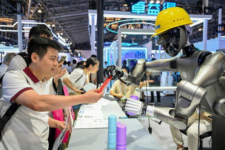 People watch a robot performing tasks at an exhibition during the World AI Conference in Shanghai. Photo: - / AFP Source: AFP