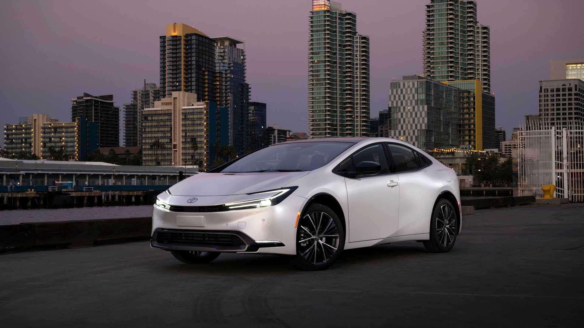 2024 Prius Limited Wind Chill Pearl Parked Out Side In Front Of City Skyline