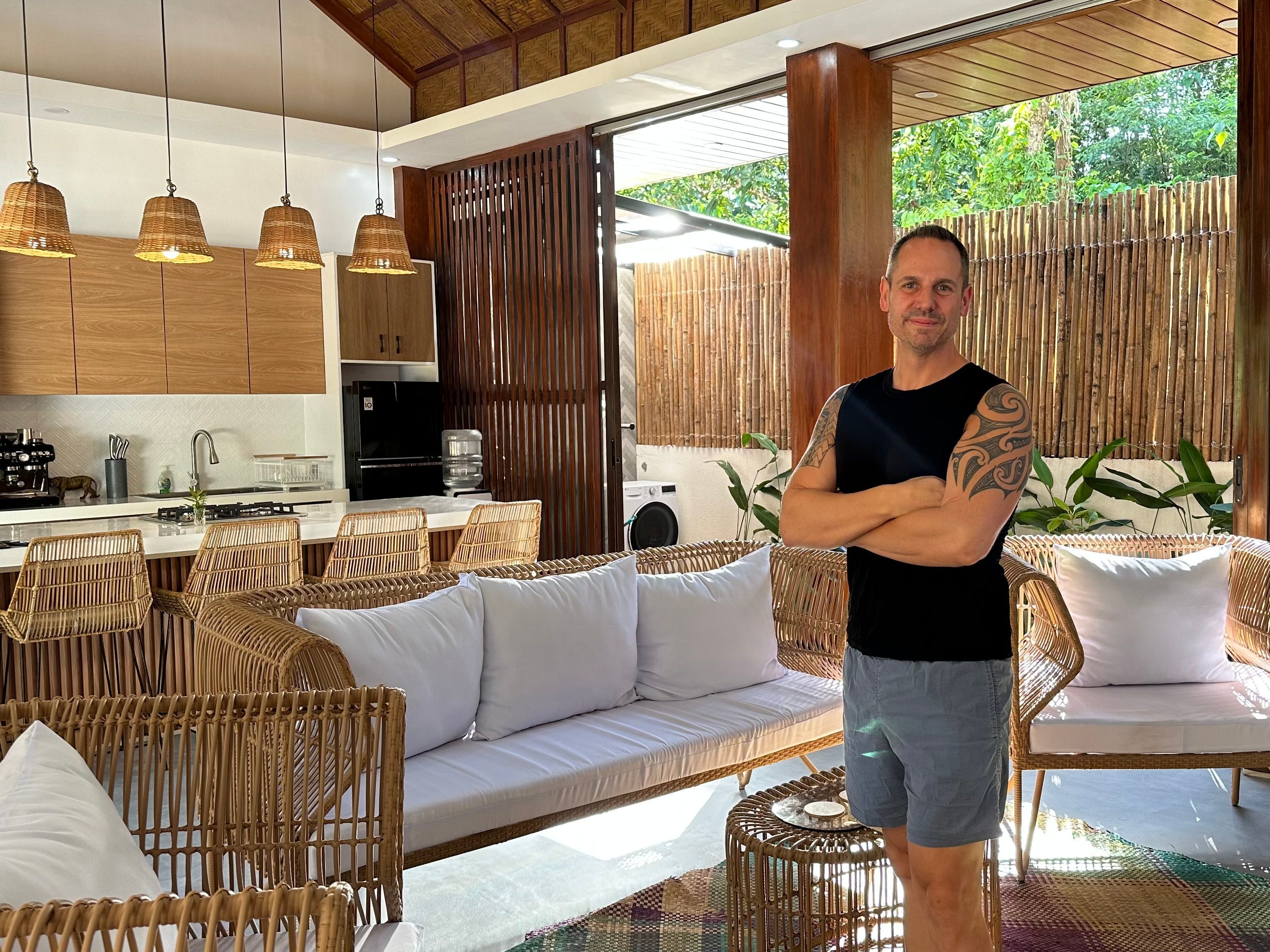 A man standing, with his arms folded, in a living room