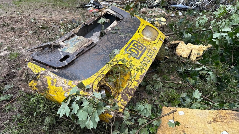 Ein Frontteil des entgleisten Personenzuges liegt in einem bewaldeten Streckenabschnitt.