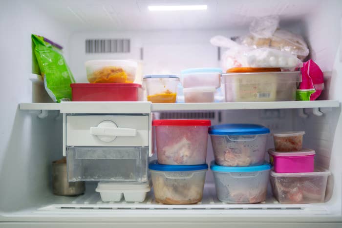 Inside view of a freezer filled with various food containers and packages, organized on shelves