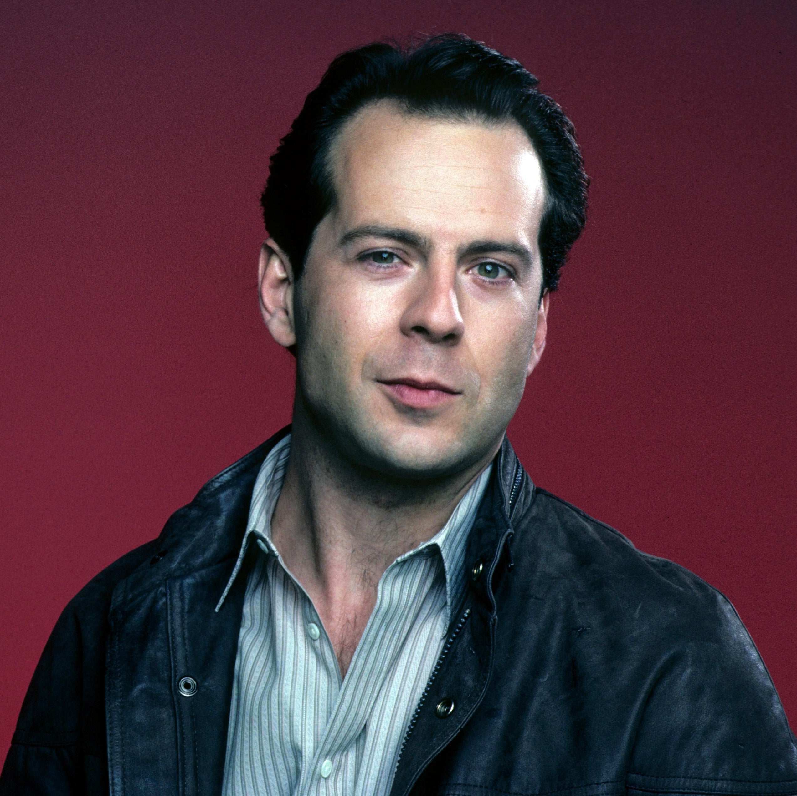 Person in a casual shirt with a leather jacket against a plain background