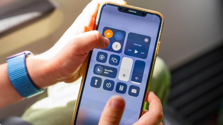 a person holding their phone and turning on airplane mode