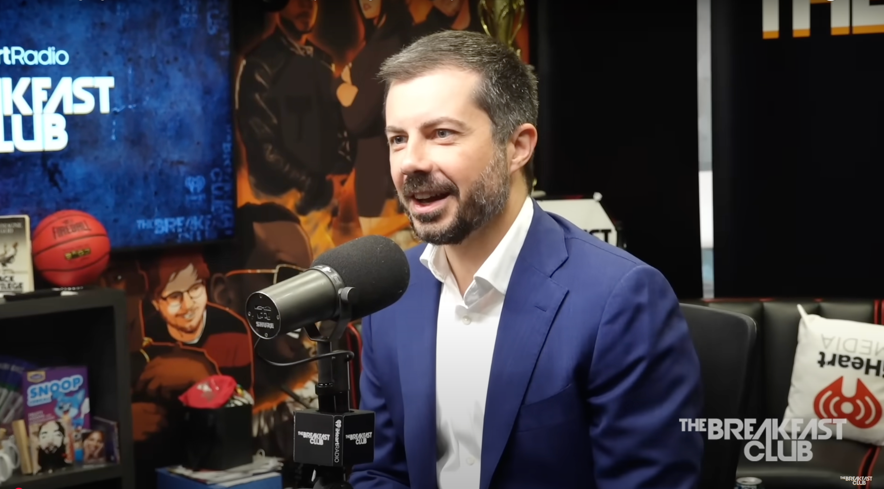 Man in a suit speaking into a microphone during a radio interview at The Breakfast Club studio