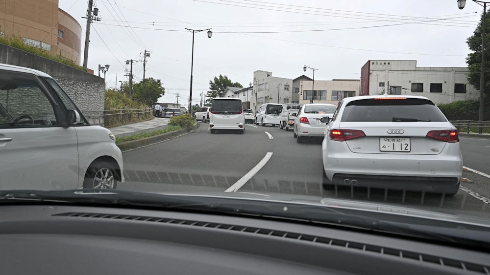 Einwohner einer Stadt auf Hokkaido fahren mit ihren Autos in höher gelegene Gebiete.