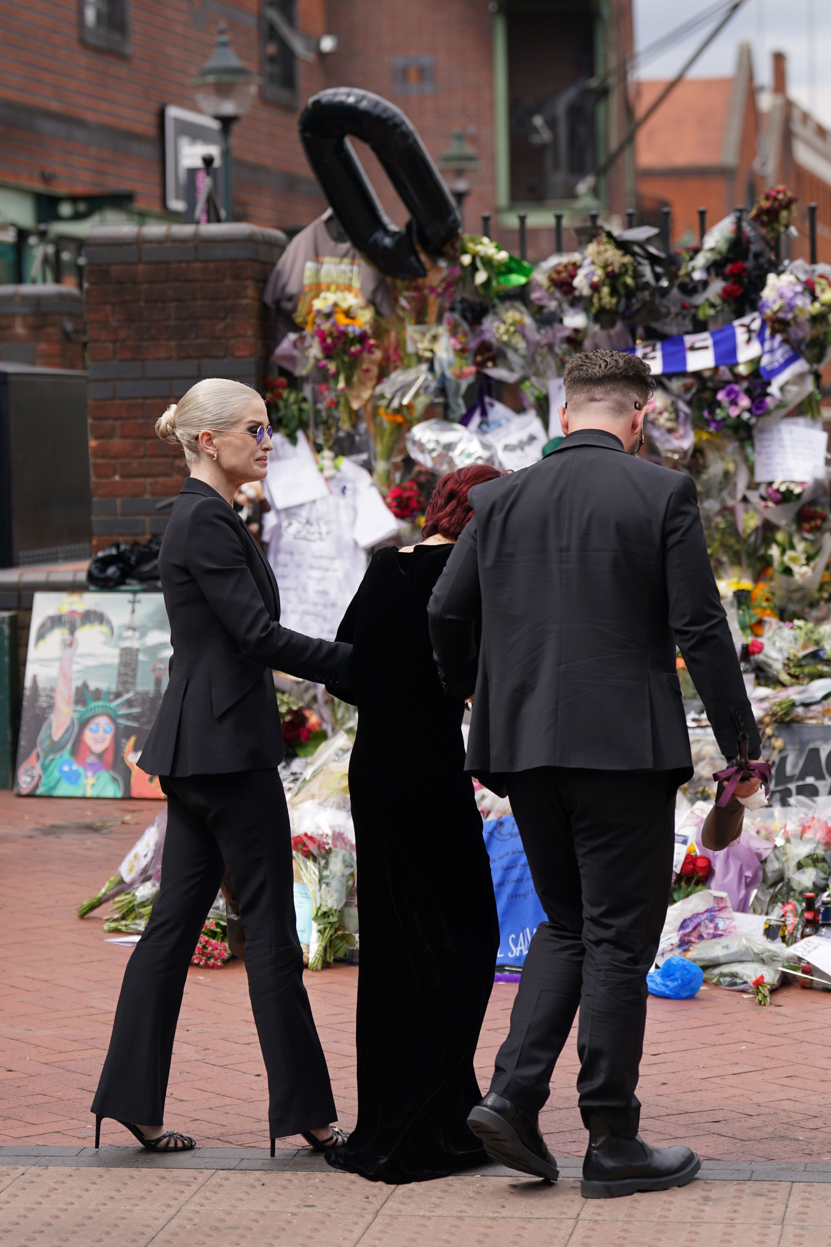 The family of Ozzy Osbourne view the messages and floral tributes left at the Black Sabbath Bridge bench (Joe Giddens/PA) (PA Wire)