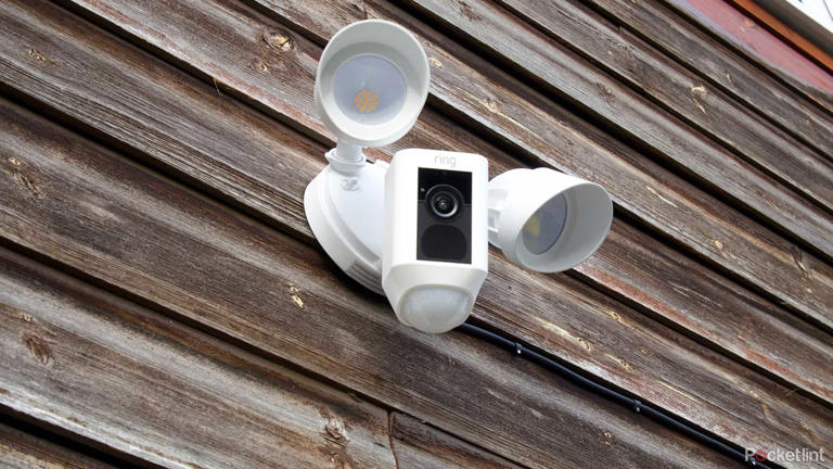 A Ring Floodlight Cam on a wooden wall. 