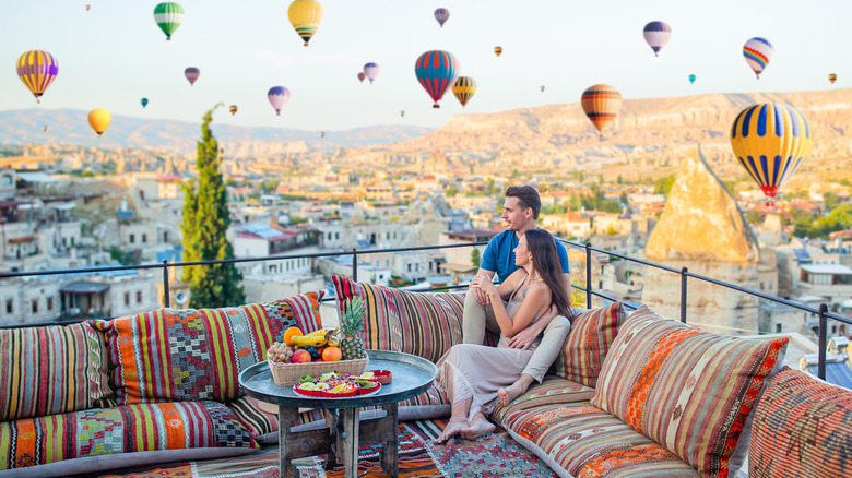 Young couple watching hot air balloons from a terrace