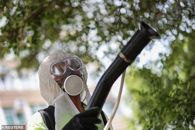 На изображениях видно, как китайские государственные служащие распыляют облака дезинфицирующего средства на городских улицах, чтобы убить комаров, переносящих вирус