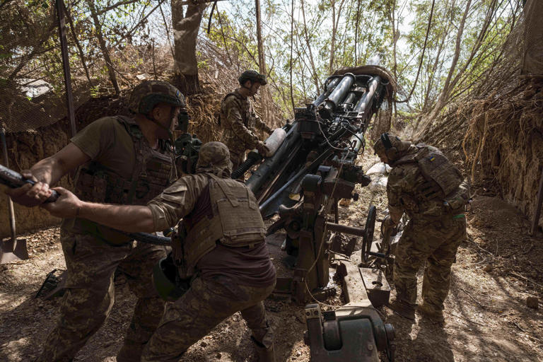 Soldados de la 148va brigada de artillería del ejército de Ucrania cargan munición en un M777 antes de disparar contra posiciones rusas en el frente, en la región ucraniana de Zaporiyia, el 7 de agosto de 2025. (AP Foto/Evgeniy Maloletka)
