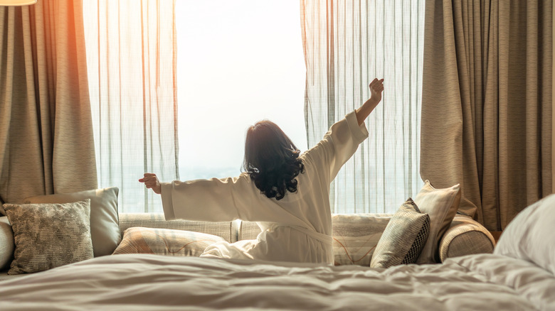 woman waking up refreshed in a hotel room
