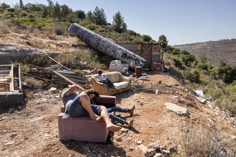People sit next to remains of an Iranian missile that fell at the settlement of Neria near Ramallah, in the occupied West Bank, on 29 June 2025, in the aftermath of the 12-day war between Israel and Iran. The 12-day war erupted on June 13, when Israel launched a bombing campaign in Iran that killed top military commanders and scientists linked to its nuclear programme. Tehran responded with ballistic missile attacks on Israeli cities. (Photo by Menahem Kahana/Getty Images
