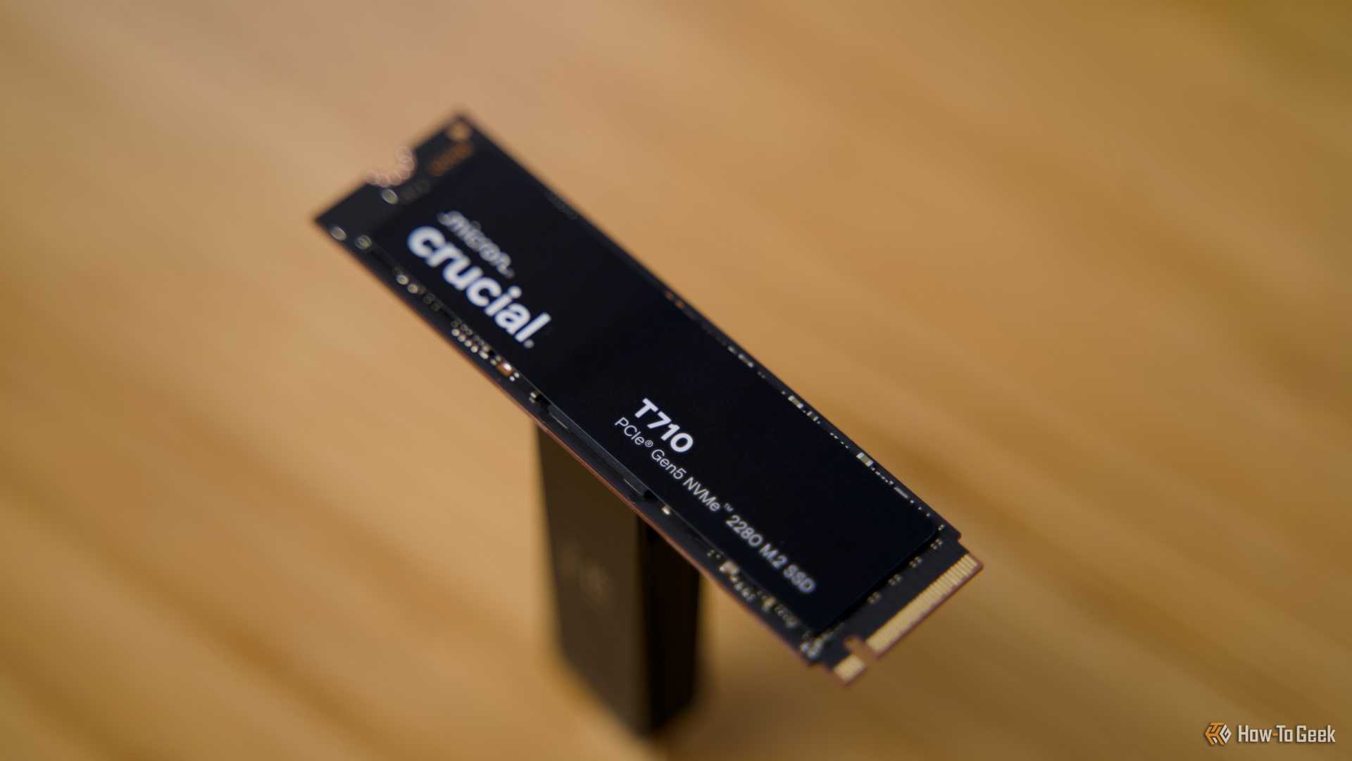 The Crucial T710 NVMe SSD raised off a bamboo desk.